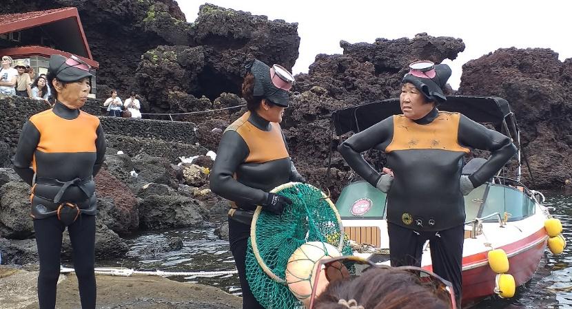 Drei ältere Taucherinnen im Tauchanzug, die sich unterhalten